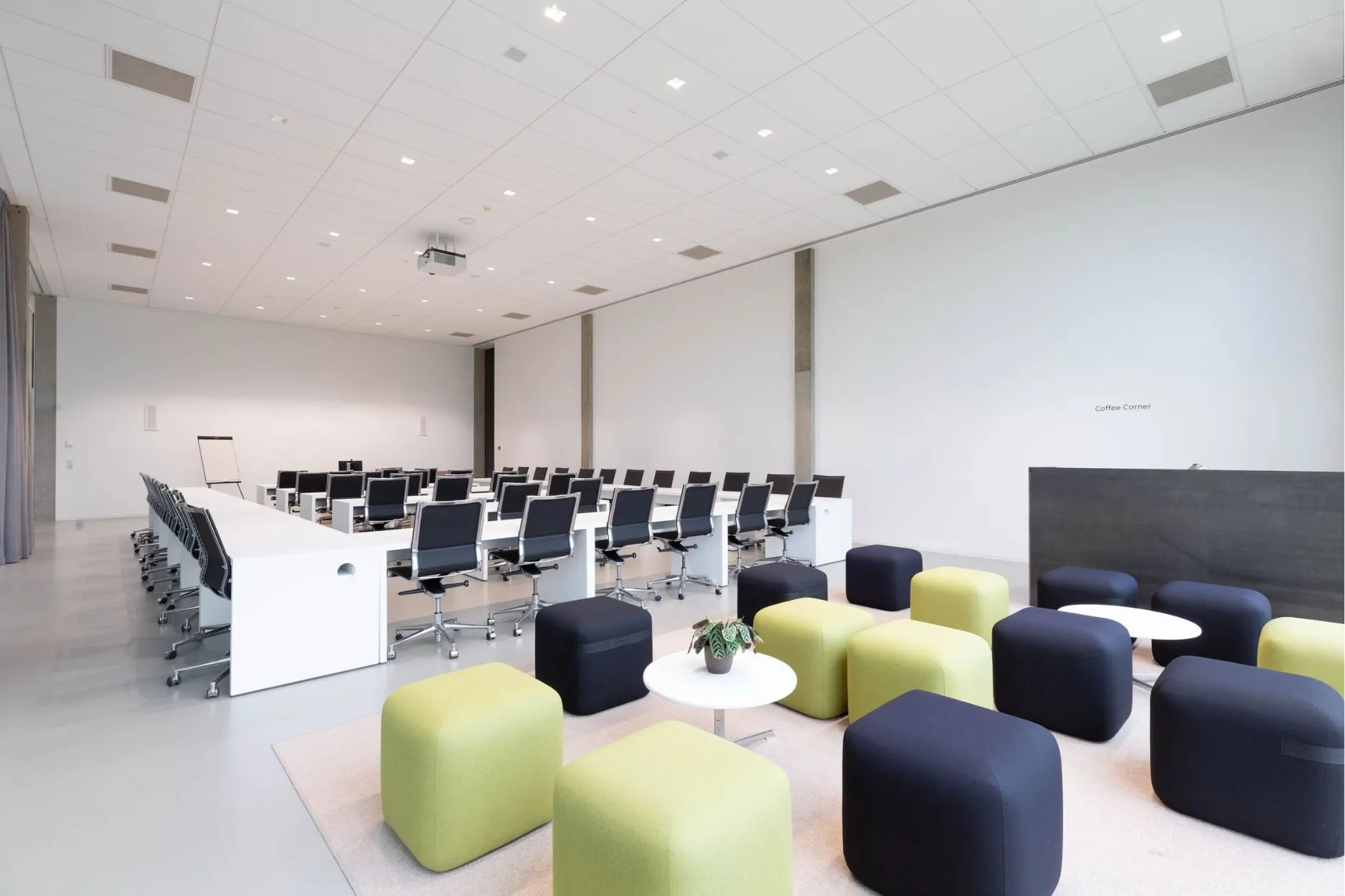 Lichte vergaderzaal in U-opstelling met kleurrijke stoelen, projectiescherm, flip-over en gordijnen als scheidingswand