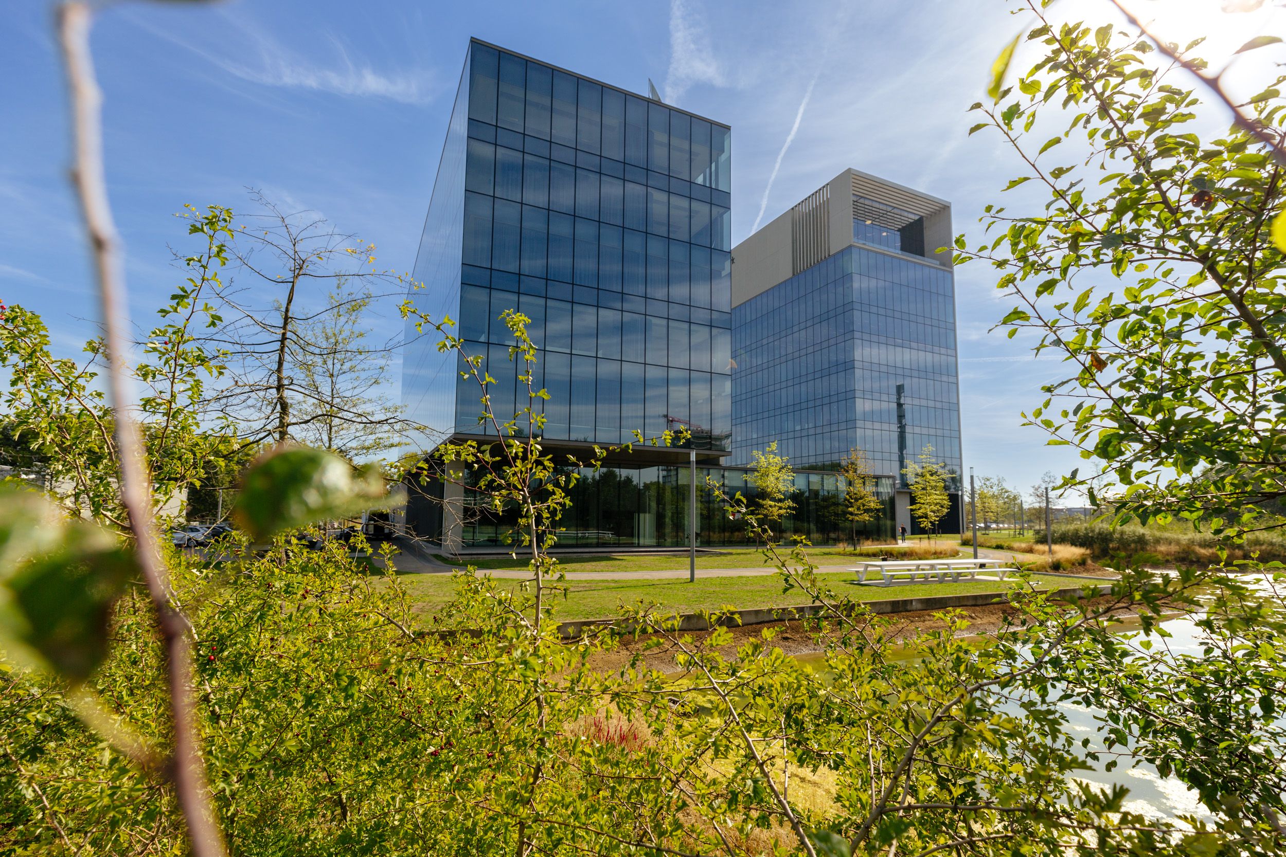 Twee moderne glazen kantoorgebouwen genaamd Skyline Park omgeven door groen park met bomen onder blauwe lucht